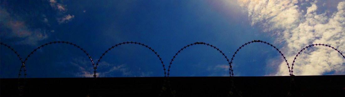Barbed wire on wall with blue sky background